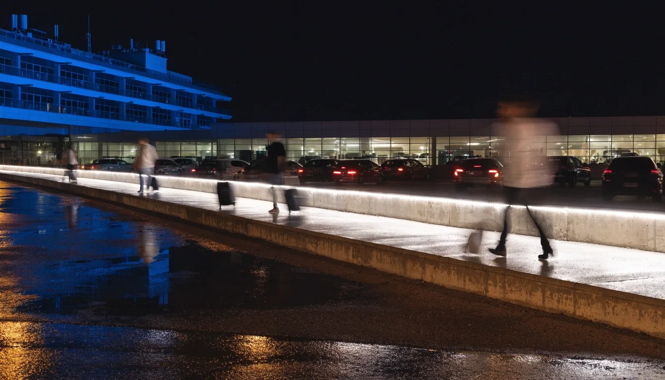 Airport terminal forecourt at night seen from a car park walkway